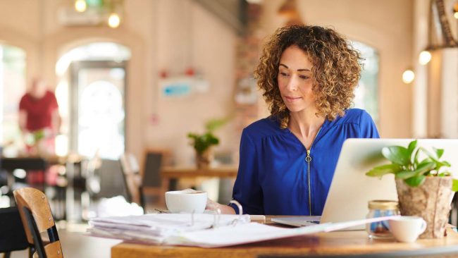 How-to-Decide-Between-Stateful-and-Stateless-VDI Young woman working at a desk with laptop and cup of coffee
