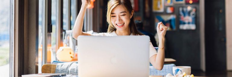 Happy young woman in from of a laptop