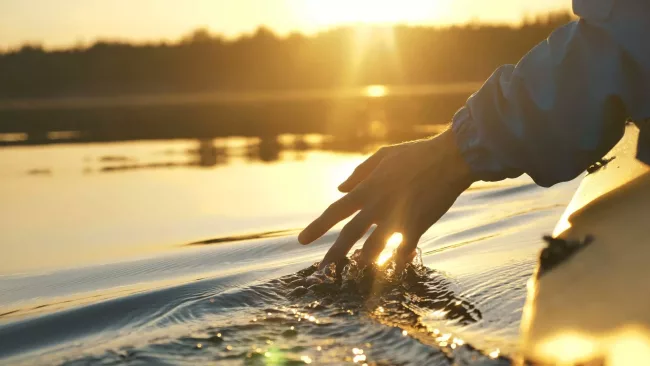Integrating-ChatGPT-to-Enhance-User-Experience_01 A hand touching water while travelling in a canoe.