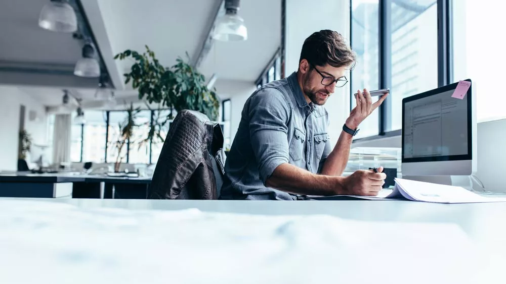 Professional male holding a phone and working in the office.