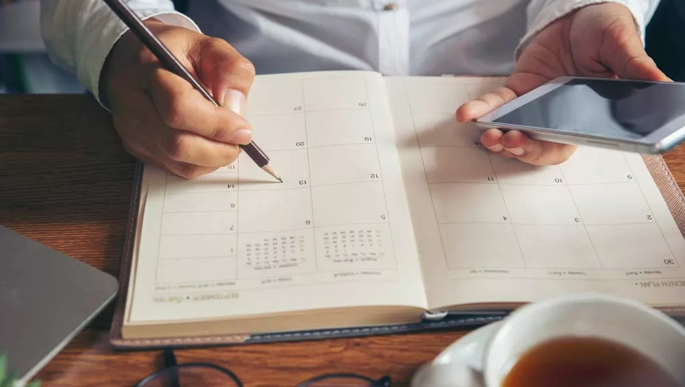 Someone is filling up a calendar - view of the hands only.